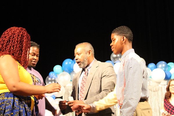 Principal Brewer offers ring to student at the Ring Ceremony.